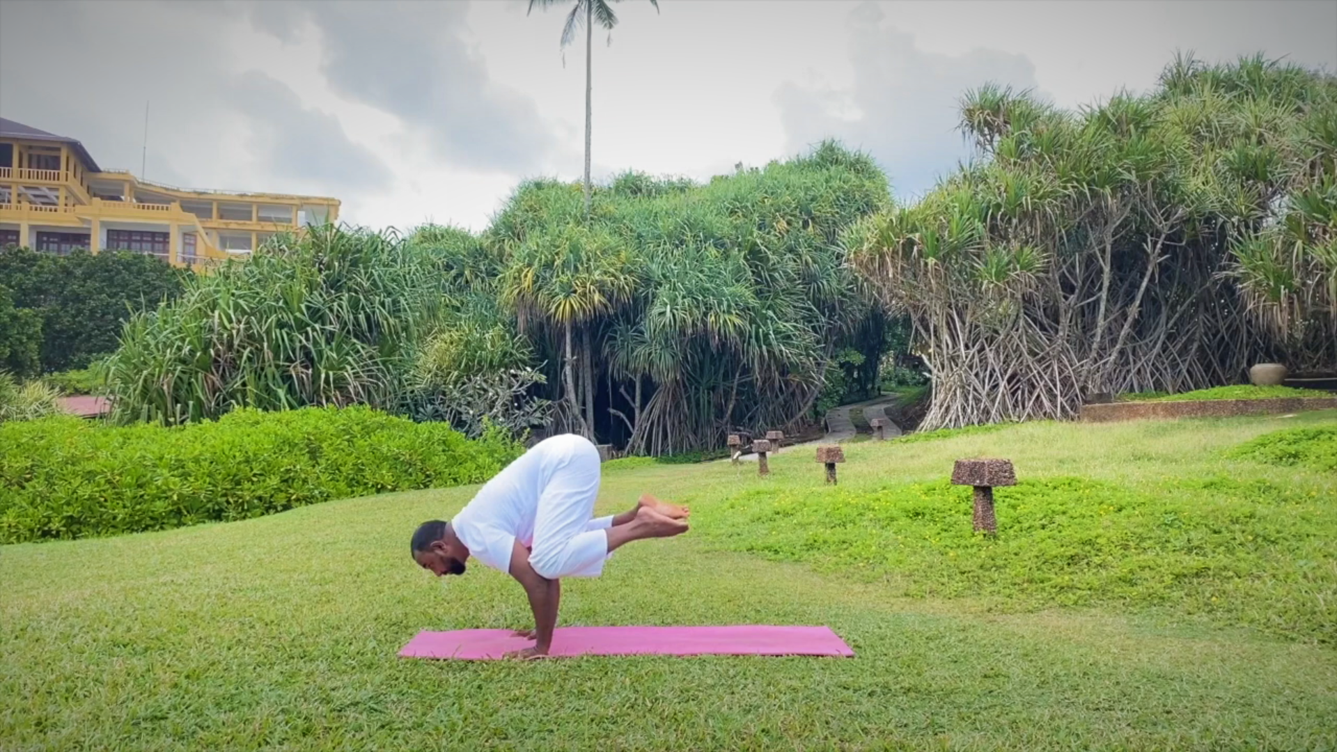 Yoga Teacher Demonstrating Crow Pose on the garden and forest behind